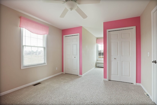 unfurnished bedroom featuring a ceiling fan, baseboards, visible vents, and multiple closets