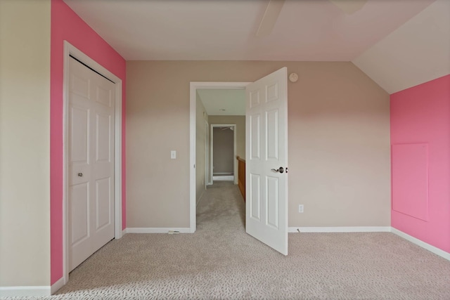 unfurnished bedroom featuring a ceiling fan, carpet, vaulted ceiling, and baseboards