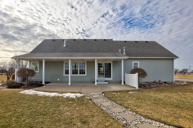 back of house with a shingled roof, a patio area, and a yard