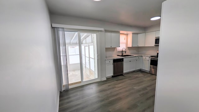 kitchen featuring dark wood-style floors, light countertops, appliances with stainless steel finishes, white cabinetry, and a sink