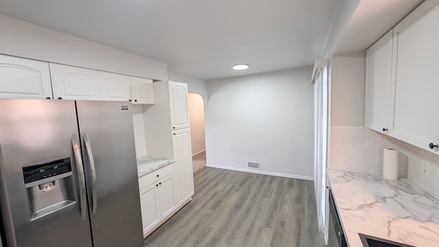 kitchen featuring decorative backsplash, light wood-style flooring, appliances with stainless steel finishes, light stone counters, and white cabinetry