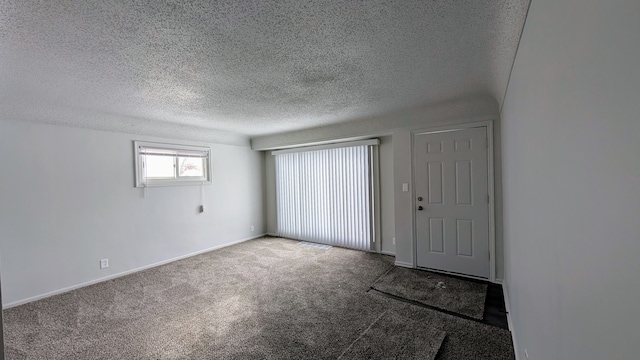 carpeted spare room featuring baseboards and a textured ceiling