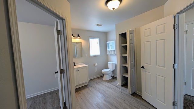 bathroom with toilet, visible vents, wood finished floors, and vanity