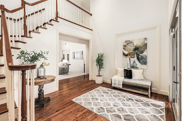 foyer entrance with dark wood-type flooring, a towering ceiling, baseboards, and stairs