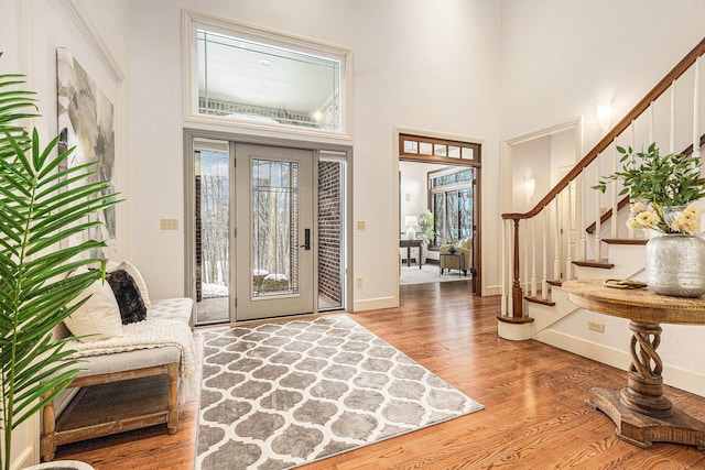 entrance foyer with stairs, a high ceiling, baseboards, and wood finished floors