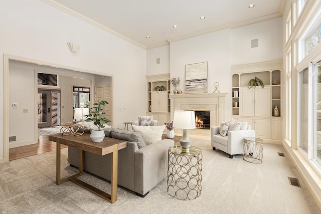 living room featuring a high ceiling, a high end fireplace, visible vents, and a healthy amount of sunlight