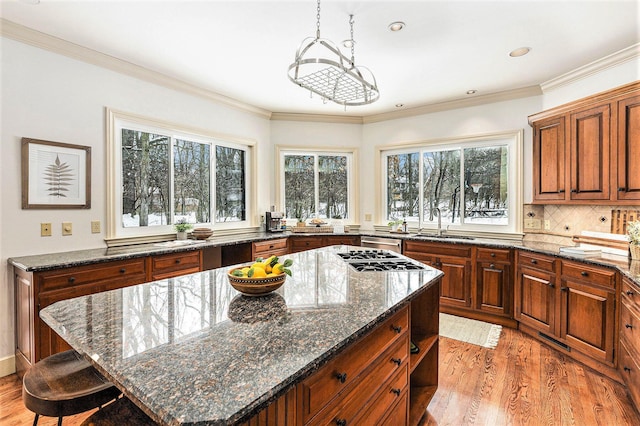 kitchen with a breakfast bar area, a kitchen island, dark stone counters, brown cabinetry, and pendant lighting