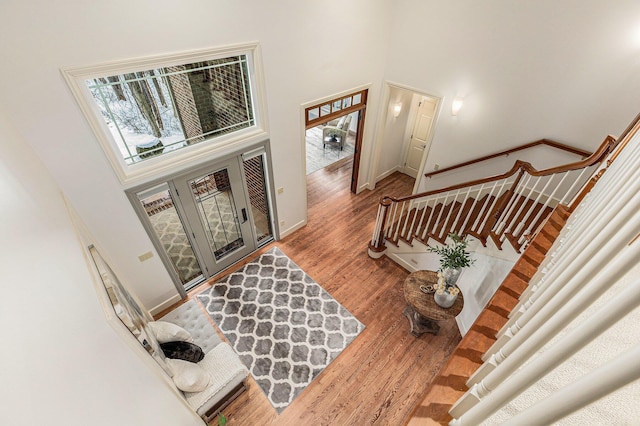 foyer entrance with baseboards, a high ceiling, stairway, and wood finished floors