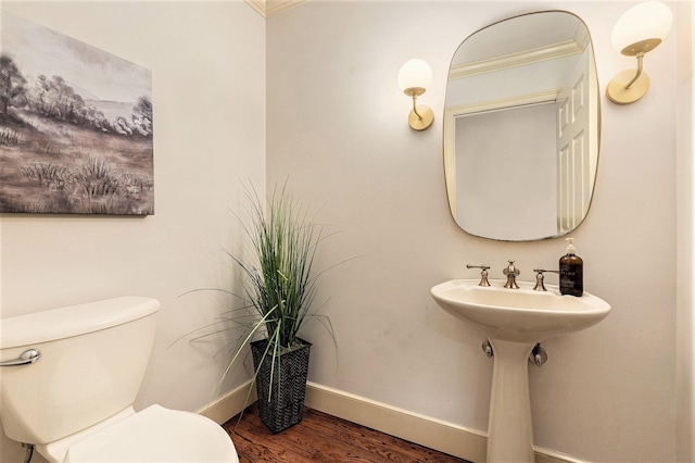 half bath with toilet, baseboards, and wood finished floors