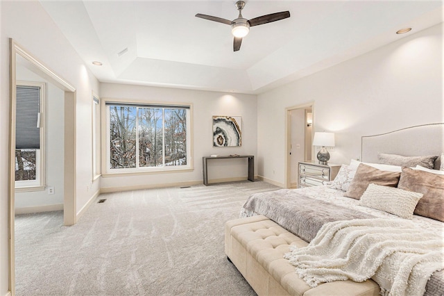 bedroom featuring visible vents, baseboards, a raised ceiling, a ceiling fan, and light colored carpet