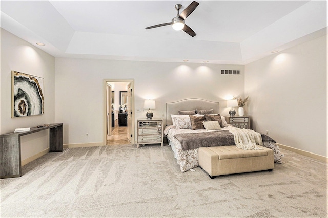 bedroom with light colored carpet, baseboards, visible vents, and a tray ceiling