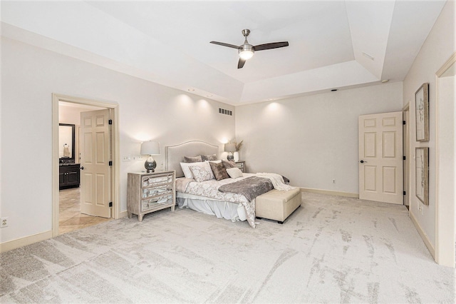 bedroom with baseboards, visible vents, a raised ceiling, and light colored carpet