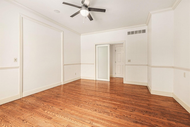 empty room with ceiling fan, ornamental molding, wood finished floors, and visible vents