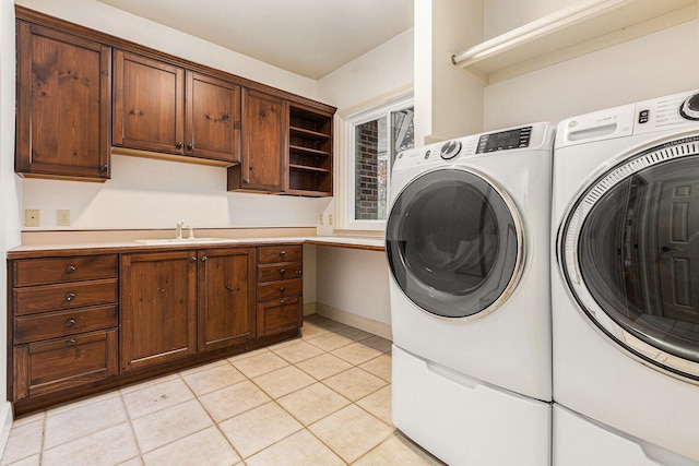 laundry room with cabinet space, light tile patterned floors, baseboards, washing machine and clothes dryer, and a sink