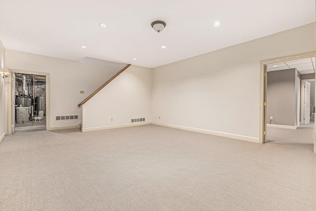 unfurnished living room featuring stairway, baseboards, visible vents, and light colored carpet