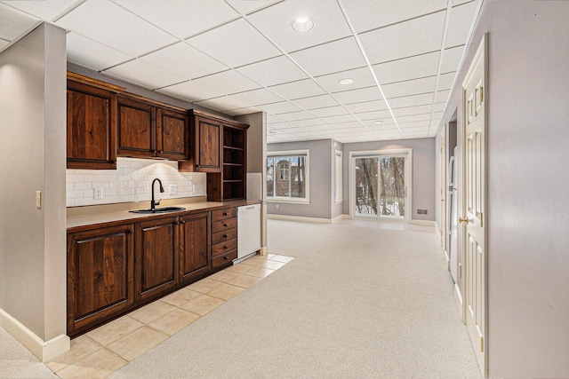 kitchen with dishwasher, light colored carpet, light countertops, open shelves, and a sink