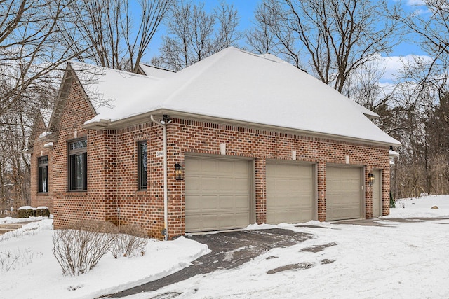 snow covered property featuring brick siding