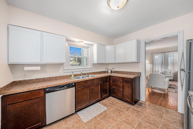 kitchen with light countertops, appliances with stainless steel finishes, a sink, and white cabinetry