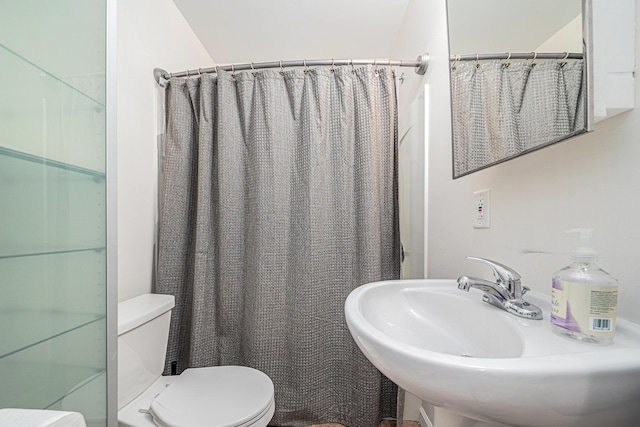 bathroom featuring a shower with shower curtain, a sink, and toilet