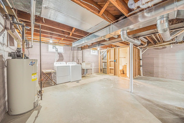 below grade area featuring washer and dryer, gas water heater, and a sink