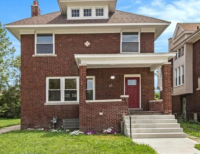 american foursquare style home featuring brick siding and a front yard