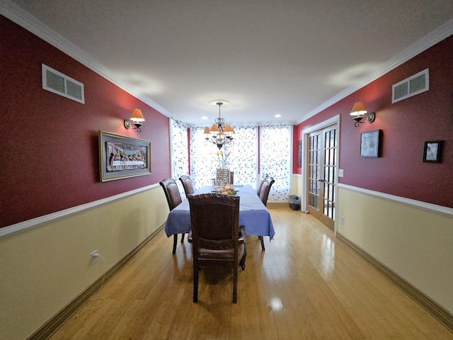 dining room with visible vents, crown molding, and light wood-style flooring