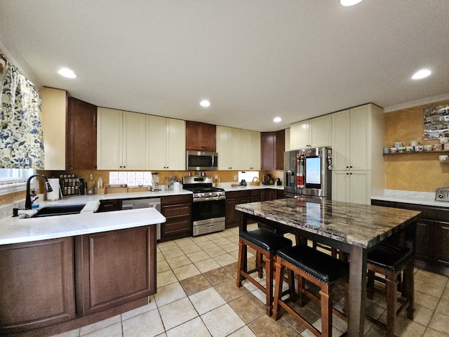 kitchen with a sink, dark brown cabinets, stainless steel appliances, and light countertops