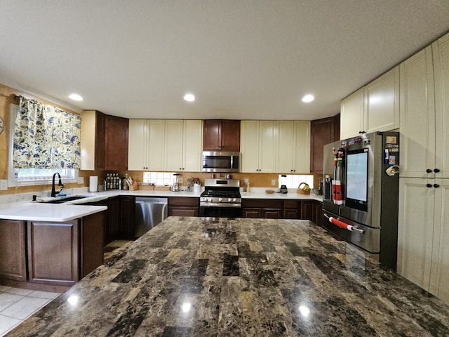 kitchen featuring recessed lighting, light countertops, appliances with stainless steel finishes, a sink, and dark brown cabinets