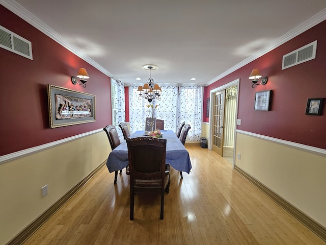 dining area featuring ornamental molding, visible vents, and light wood-style floors