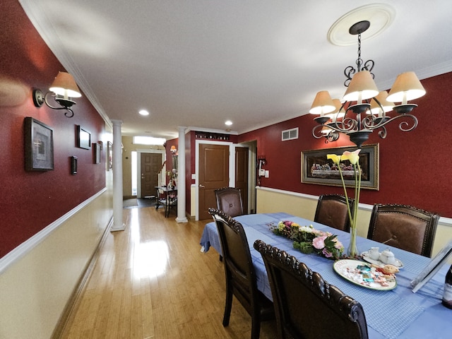 dining area with a chandelier, light wood-style floors, visible vents, and crown molding