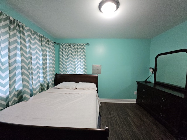 bedroom with dark wood-style flooring and baseboards