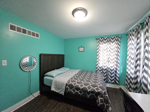 bedroom with visible vents, baseboards, and wood finished floors