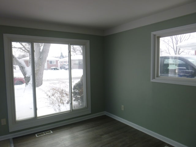 spare room with dark wood-style floors, visible vents, and baseboards