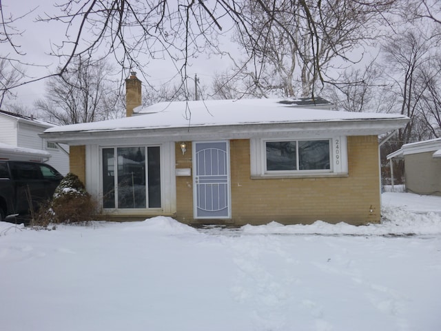 view of front of property featuring brick siding and a chimney