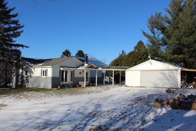 view of snowy exterior with an outbuilding, brick siding, a detached garage, a chimney, and solar panels