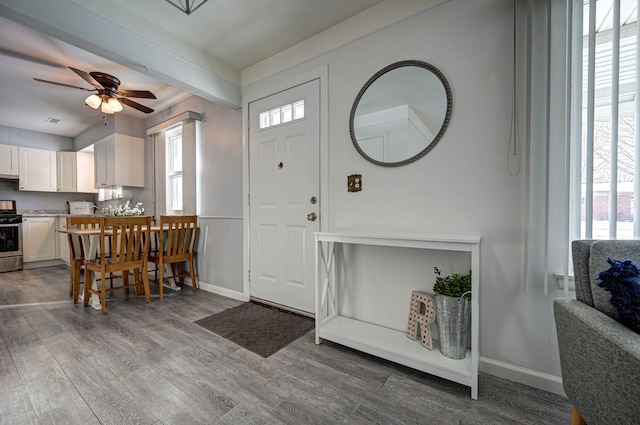 foyer entrance featuring ceiling fan, wood finished floors, beam ceiling, and baseboards