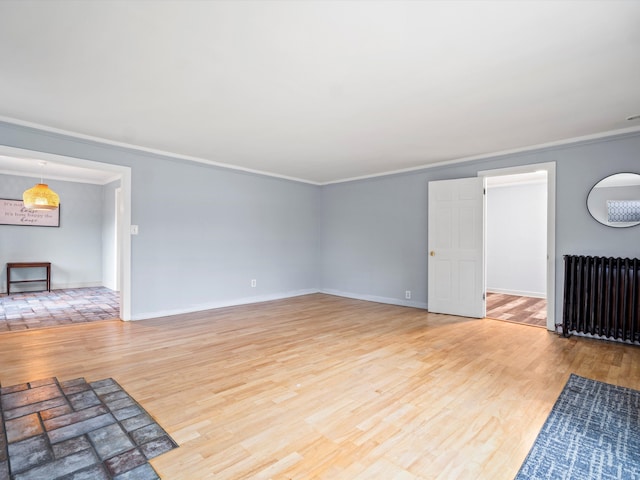 unfurnished living room with baseboards, radiator heating unit, wood finished floors, and crown molding