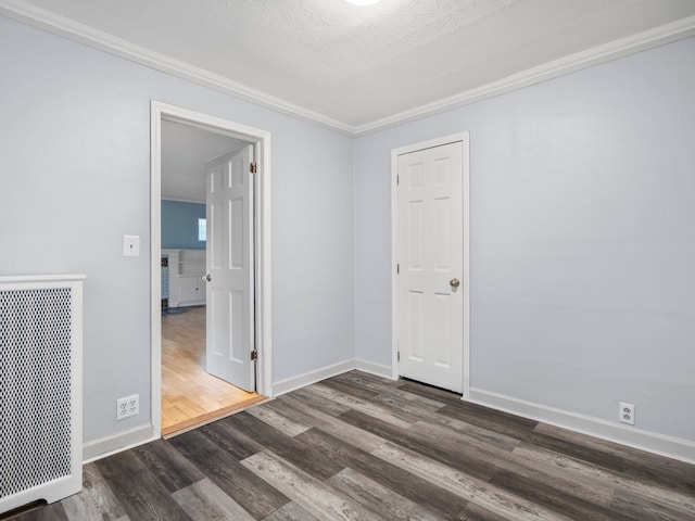 unfurnished room with a textured ceiling, baseboards, dark wood-style flooring, and ornamental molding