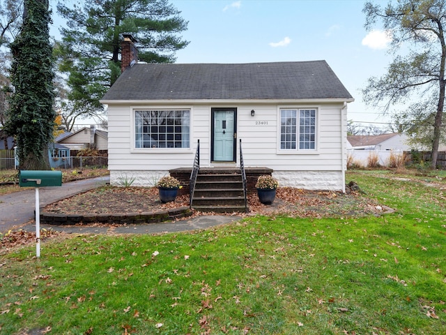 bungalow-style house with entry steps, a front lawn, a chimney, and fence