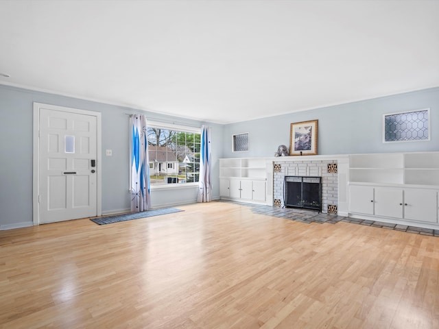 unfurnished living room with light wood finished floors, a fireplace, and baseboards