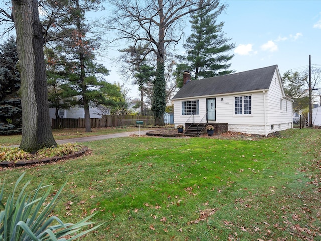 view of front of home with a front yard, fence, and a chimney