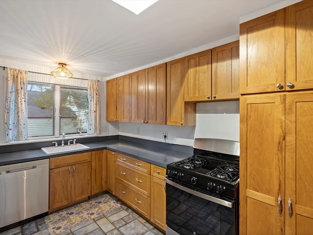 kitchen with range with gas cooktop, dark countertops, stainless steel dishwasher, brown cabinetry, and a sink