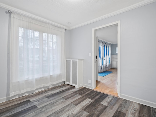 spare room featuring dark wood-style floors, baseboards, visible vents, and crown molding