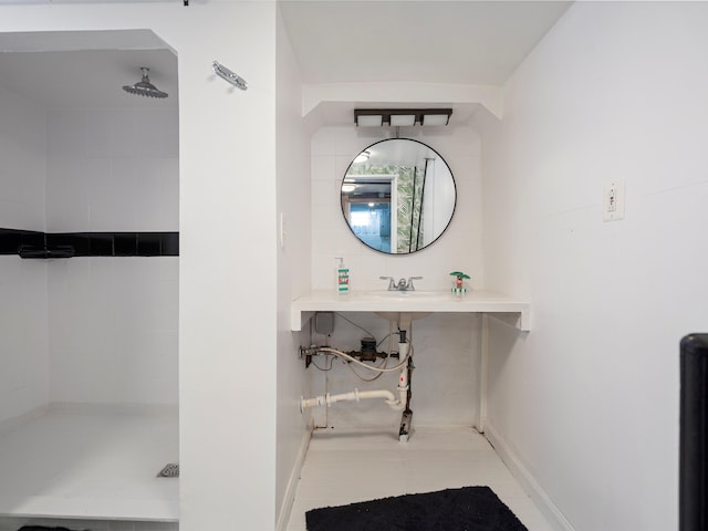 full bath with tiled shower and baseboards