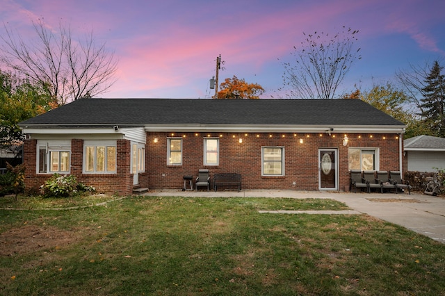 view of front of property with a patio area, a lawn, and brick siding