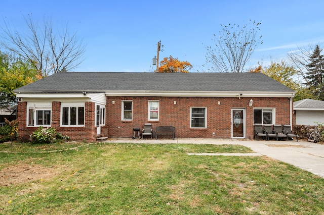 rear view of property with entry steps, brick siding, a lawn, and a patio area