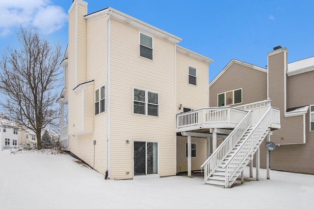 snow covered property featuring a chimney, stairway, and a deck