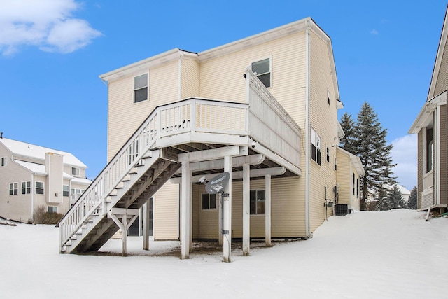 snow covered back of property featuring stairs