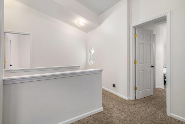 hallway with lofted ceiling, carpet, and baseboards