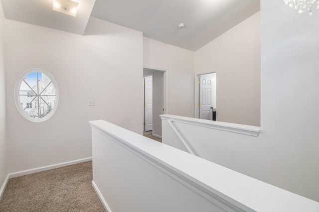 corridor with baseboards, carpet flooring, vaulted ceiling, and an upstairs landing